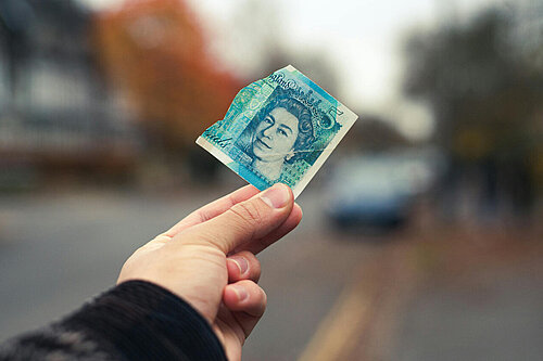 man holding a £5 note out