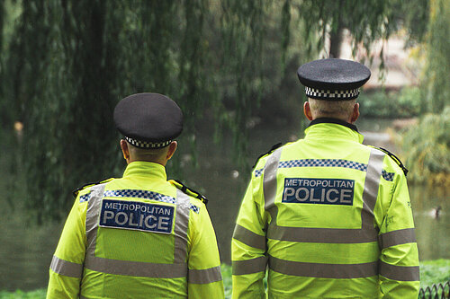 Two male police officers walking next to a canal